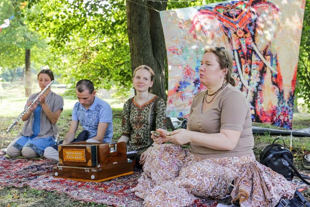 Muzicieni cântă kirtan în parc: flaut, armoniu și kartale